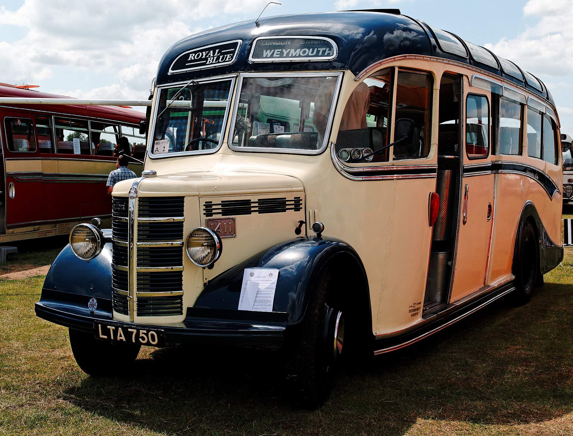 Cream and dark blue 1940s Bedford OB coach with polished chrome radiator grille, destination blind reading Weymouth, on grass at a vintage vehicle rally